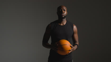 Studioporträtaufnahme-Eines-Männlichen-Basketballspielers,-Der-Mit-Dem-Ball-Auf-Die-Kamera-Zuläuft